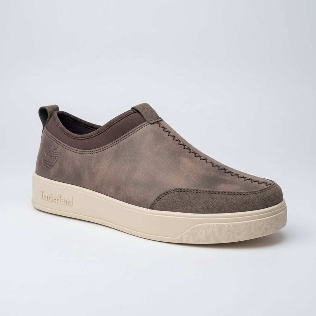 Brown Timberland shoe held in front of green foliage