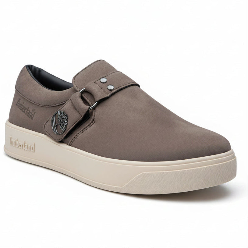 Brown slip-on shoe with a strap on a gray background