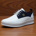 White sneaker with navy accents held by a hand on a grassy background