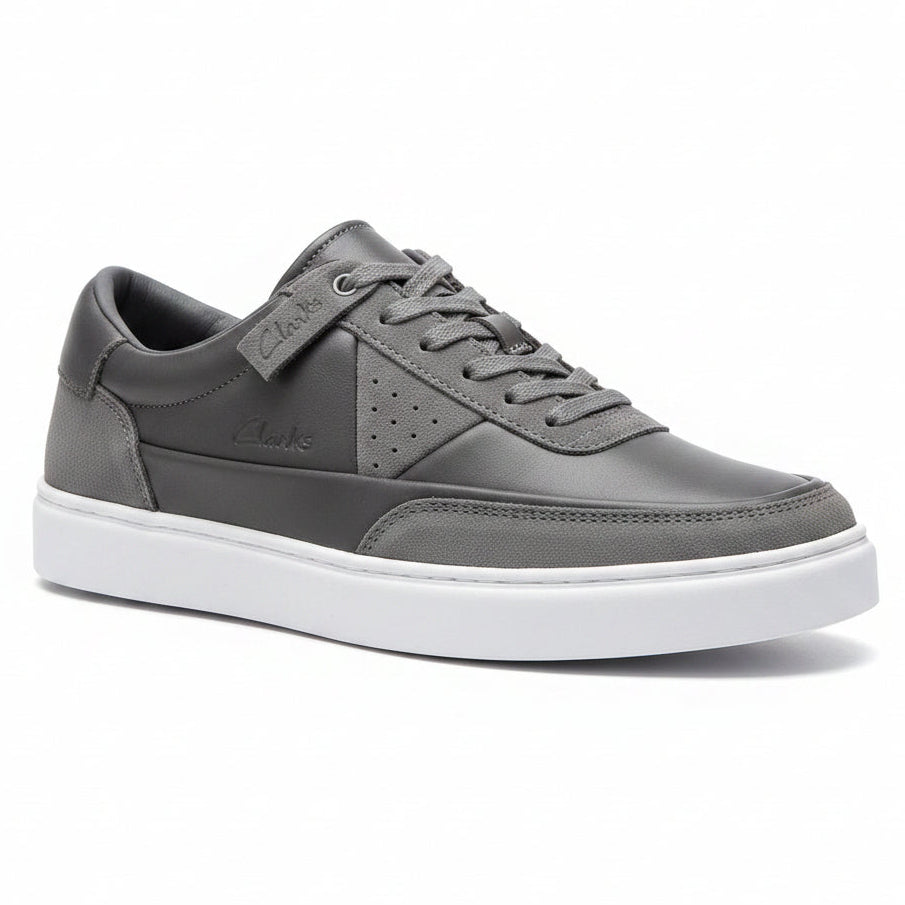 Gray sneaker held by a hand with a colorful bracelet on a wooden floor background