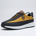 Yellow and black sneakers with white soles on a wooden surface.