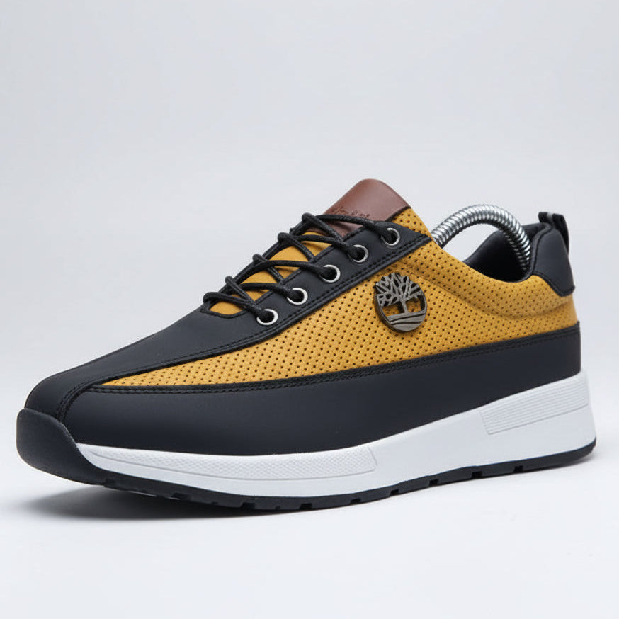 Yellow and black sneakers with white soles on a wooden surface.