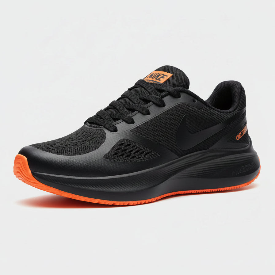 Black and gray sneaker with orange accents held by a person, blurred background
